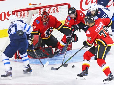 The Calgary Flames look to clear a loose puck during NHL action against the Winnipeg Jets at the Scotiabank Saddleome in Calgary on Saturday January 20, 2018.