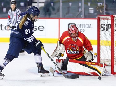 The Mount Royal University Cougars' Kate Hufnagel reaches for the rebound off the pads of University of Calgary Dinos goalie Kelsey Roberts during the Crowchild Classic at the Scotiabank Saddledome in Calgary, Thursday January 25, 2018.