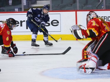 The Mount Royal University Cougars' Nicolette Spencer fires a pass across the ice in front of University of Calgary Dinos goalie Kelsey Roberts during the Crowchild Classic at the Scotiabank Saddledome in Calgary, Thursday January 25, 2018.