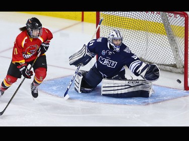 University of Calgary Dinos forward Rylee Smith and The Mount Royal University Cougars goaltender Zoe De Beauville track a puck as it flies across the crease during the Crowchild Classic at the Scotiabank Saddledome in Calgary on Thursday January 25, 2018.