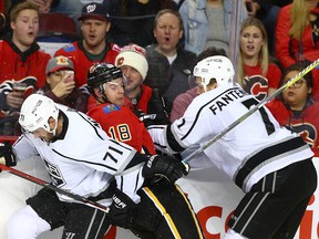 Flames Matt Stajan is checked by Kings Torrey Mitchell, left, and Oscar Fantenberg at the Saddledome on Thursday, Jan. 4, 2018.