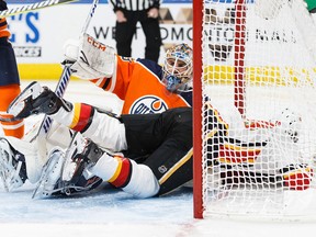 Goaltender Cam Talbot  of the Edmonton Oilers sits underneath Matthew Tkachuk of the Calgary Flames at Rogers Place on January 25, 2018 in Edmonton, Canada.