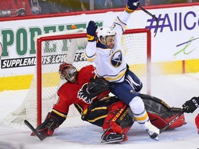 The Buffalo Sabres Nicholas Baptiste falls on Calgary Flames goaltender Mike Smith during NHL action at the Scotiabank Saddledome on Calgary on Monday. Photo by Gavin Young/Postmedia.