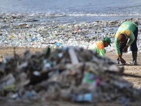 This photo taken on Dec. 19, 2017 shows rubbish collectors clearing trash on Kuta beach near Denpasar, on Indonesia's tourist island of Bali. (SONNY TUMBELAKA/AFP/Getty Images)