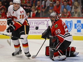 The puck bounces between Matthew Tkachuk #19 of the Calgary Flames and Corey Crawford #50 of the Chicago Blackhawks at the United Center on November 1, 2016 in Chicago, Illinois.  (Photo by Jonathan Daniel/Getty Images)