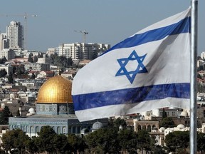 The Israeli flag flutters in front of the Dome of the Rock mosque and th city of Jerusalem, on December 1, 2017.