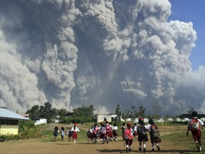 School children walk as Mount Sinabung erupts in Karo, North Sumatra, Indonesia, Monday, Feb. 19, 2018. Rumbling Mount Sinabung on the Indonesian island of Sumatra has shot billowing columns of ash more than 5,000 meters (16,400 feet) into the atmosphere and hot clouds down its slopes. The volcano, one of three currently erupting in Indonesia, was dormant for four centuries before exploding in 2010.