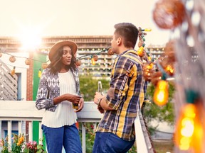 Two young casual friends having a casual conversation at an urban celebration with a cityscape view in the evening. Getty Images/iStockphoto