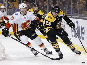 Flames' Mark Jankowski (77) battles Bruins' Brandon Carlo (25) for the puck during NHL action in Boston, Tuesday, Feb. 13, 2018.