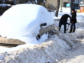 Bonnie and Neal Sanch shovel a pile of ice and snow from the front of their northwest Calgary house on  Saturday, February 10, 2018. The house is on a snow route and they were shovelling snow piled up by plows to be able to access the sidewalk leading to the front of the house. The car on the street belongs to a neighbour and has been ticketed once during the snow ban.