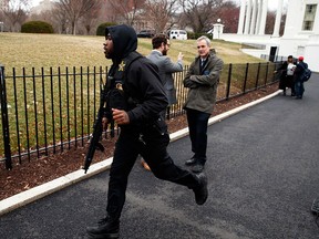A Secret Service officer rushes past reporters after a vehicle rammed a barrier near the White House, Friday, Feb. 23, 2018, in Washington. (AP Photo/Evan Vucci)