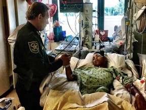 This image made available by the Broward County Sheriff's Office on Feb. 18, 2018, shows Sheriff Scott Israel, holding the hand of Anthony Borges, 15, a student at Marjory Stoneman Douglas High School.