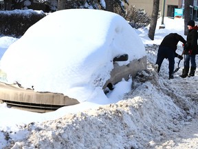 Residents in northwest Calgary dig out on a snow route on Feb. 10. Another snow route parking ban is in effect.