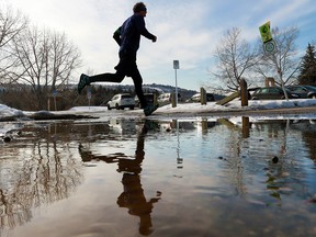 A runner is reflected in a puddle of melting snow on the Bow River pathway near Edworthy Park on a warm second official day of spring, Wednesday March 21, 2018. Gavin Young/Postmedia