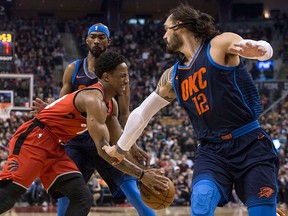 Toronto Raptors guard DeMar DeRozan (left) drives between Oklahoma City Thunder's Corey Brewer and Steven Adams (right) during first half NBA basketball action in Toronto on Sunday, March 18, 2018. THE CANADIAN PRESS/Chris Young