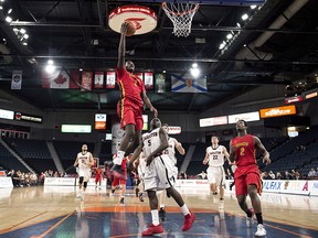 Calgary Dinos' Mambi Diawara, left, scores in front of Carleton Ravens' Emmanuel Owootoah, centre, in Halifax on Thursday, March 9, 2017. (THE CANADIAN PRESS/Darren Calabrese)