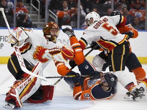 Edmonton Oilers Connor McDavid is stopped by Flames goaltender David Rittich and Mark Giordano in Edmonton on Jan. 25, 2018.