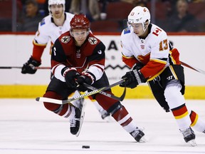 Arizona Coyotes defenseman Jakob Chychrun (6) battles with Calgary Flames left wing Johnny Gaudreau (13) for the puck during the first period of an NHL hockey game Monday, March 19, 2018, in Glendale, Ariz.