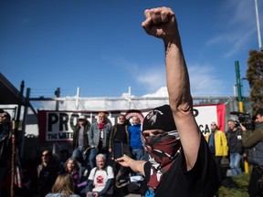 A protester raises his fist as others block a gate outside Kinder Morgan, in Burnaby, B.C., on Saturday March 17, 2018. Approximately 30 people who blockaded an entrance - defying a court order - were arrested while protesting the Kinder Morgan Trans Mountain pipeline expansion. The pipeline is set to increase the capacity of oil products flowing from Alberta to the B.C. coast to 890,000 barrels from 300,000 barrels.