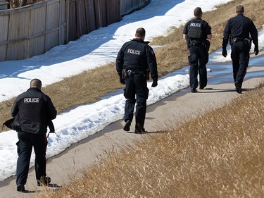 Police officers walk back to their vehicles after containing the scene were an officer was shot in Abbeydale in Calgary on Tuesday March 27, 2018.
