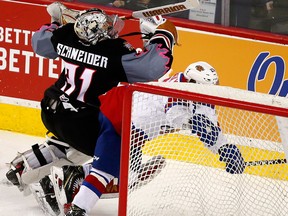 Calgary Hitmen goalie Nick Schneider takes a hit from Edmonton Oil Kings Trey Fix-Molansky during second-period action at the Scotiabank Saddledome in Calgary on Sunday, March 18, 2018.