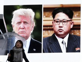 A woman walks by a huge screen showing U.S. President Donald Trump, left, and North Korea's leader Kim Jong Un, in Tokyo, Friday, March 9, 2018.