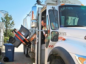 A City of Calgary employees operates an automated garbage collection truck.