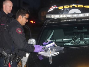 Police officers sort through items at the scene of the stabbing on  November 17, 2016 in northeast Calgary's Coral Springs neighbourhood.