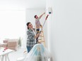 Home makeover and renovation: young happy couple painting their new house interiors using paint rollers