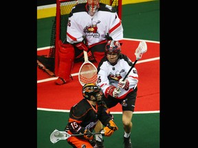 The Buffalo Bandits Shawn Evans looks for opening while harassed by the Calgary Roughnecks' Chad Cummings during a National Lacrosse League game in Calgary on Saturday April 14, 2018.