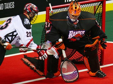 The Calgary Roughnecks' Tyler Digby flies in for a shot on  Buffalo Bandits goaltender Alex Buque during a National Lacrosse League game in Calgary on Saturday April 14, 2018.