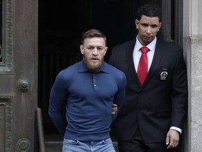 Ultimate fighting star Conor McGregor is led by an official to an unmarked vehicle while leaving the 78th Precinct of the New York Police Department on April 6, 2018