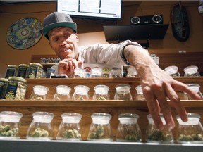 In this Sept. 28, 2015, file photo, Shane Cavanaugh, owner of Amazon Organics, a pot dispensary in Eugene, Ore., arranges the cannabis display in his store.