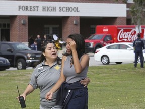 A student is comforted by a school official as students are led out of Forest High School after a shooting at the school on Friday, April 20, 2018 in Ocala, Fla.
