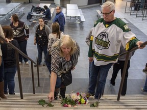 Humboldt mayor Rob Muench, in the Broncos jersey, along with other mourners lay down flower on the stairs that enter to Elgar Petersen Arena, home of the Humboldt Broncos, in Humboldt, Sask., on Saturday, April 7, 2018. RCMP say 14 people are dead and 14 people were injured Friday after a truck collided with a bus carrying a junior hockey team to a playoff game in northeastern Saskatchewan. Police say there were 28 people including the driver on board the Humboldt Broncos bus when the crash occurred at around 5 p.m. on Highway 35 north of Tisdale.