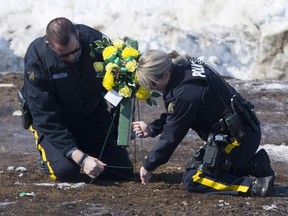 Members of the RCMP lay flowers at the intersection of a crash site near Tisdale, Sask., Sunday, April, 8, 2018. A bus carrying the Humboldt Broncos hockey team crashed into a truck en route to Nipawin for a game Friday night killing 15 and sending over a dozen more to the hospital.