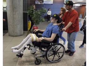 Humboldt Broncos hockey player Ryan Straschnitzki, who was paralyzed following a bus crash that killed 16 people, is wheeled by his father Tom as his mother Michelle, centre, walks beside in Calgary, Alta., Wednesday, April 25, 2018.THE CANADIAN PRESS/Jeff McIntosh ORG XMIT: JMC107