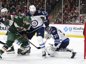 Minnesota Wild left wing Marcus Foligno is stopped by Jets goalie Connor Hellebuyck with defensive help from Tyler Myers in the first period on Sunday, April 15, 2018, in St. Paul, Minn.