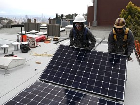 Luminalt solar installers Pam Quan (L) and Walter Morales (R) install solar panels on the roof of a home on May 9, 2018 in San Francisco, California.