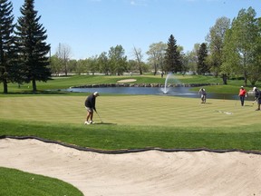 Golfers putt on the 18th green with the 10th green and fountain in the background at the Inglewood Golf and Country Club in southeast Calgary on Saturday, May 19, 2018.