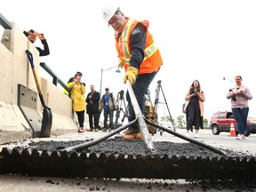 Calgary Mayor Naheed Nenshi works on filling a pothole with City crews during a visit to a road crew filling potholes on 14 St NW in Calgary on TuesdayMay 29, 2018. Crews have been out since early April and have filled more than 3500 in the past two months. Jim Wells/Postmedia