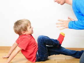 In this stock photo, a boy attempt to kick his father on the floor of their home.