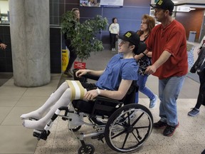 Humboldt Broncos hockey player Ryan Straschnitzki, who was paralyzed following a bus crash that killed 16 people, is wheeled by his father Tom as his mother Michelle, centre, walks beside in Calgary, Alta., Wednesday, April 25, 2018. THE CANADIAN PRESS/Jeff McIntosh