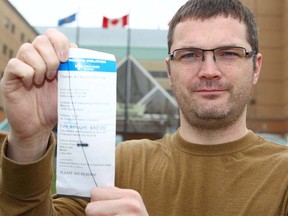 Chris Martin holds up the parking ticket he received shortly after he and his wife arrived at Alberta Children's Hospital with their sick baby. The hospital forgave the ticket. Martin is photographed on May 9, 2018 at Peter Lougheed Hospital, where his son is being treated.