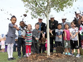 Colleen De Neve/ Calgary Herald CALGARY, AB -- SEPTEMBER 10, 2015 -- St. Jerome Grade 1 students joined dignitaries including, back row from left, St. Jerome principal David Gustavson, Calgary Mayor Naheed Nenshi, Councillor Jim Stevenson and Nico Bernard, Manager of the ReTree YYC program during a ceremony to celebrate the replanted trees at St. Jerome School on September 10, 2015. The ceremony was held on the year anniversary of Snowtember which saw damage to more than 50 per cent of Calgary's urban canopy. (Colleen De Neve/Calgary Herald) (For City story by Eva Ferguson) 00068331A SLUG: 0911-Snowtember