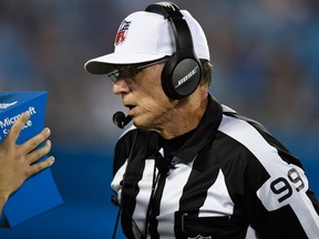 In this Wednesday, Aug. 9, 2017 photo, referee Tony Corrente looks at the instant replay on a Microsoft Surface tablet