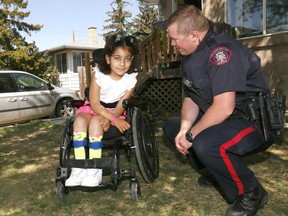 Julia,8, speaks with Calgary police Const. Mike Kornelson who delivered her stolen wheelchair back after her family's van and Julia's wheelchair were stolen a couple days ago in Calgary on Saturday May 26, 2018. Darren Makowichuk/Postmedia