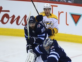 Winnipeg Jets goaltender Connor Hellebuyck makes a save as Nashville Predators centre Kyle Turris (top) is defended by Mathieu Perreault during Game 6.