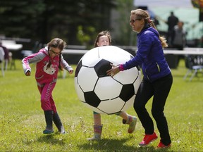 Christy Schaefer, right, has fun with fellow Sunnyside neighbours Mya Emmons, 10 and her sister Kensie, 7, during Neighbour Day in Calgary, on Saturday June 16, 2018. Leah Hennel/Postmedia