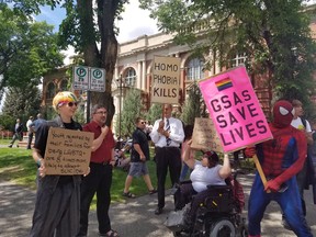People hold signs outside of a courthouse in Medicine Hat on Wednesday, June 20, 2018. A big crowd showed up for the first court challenge to an Alberta law barring schools from telling parents if their children join a gay-straight alliance.